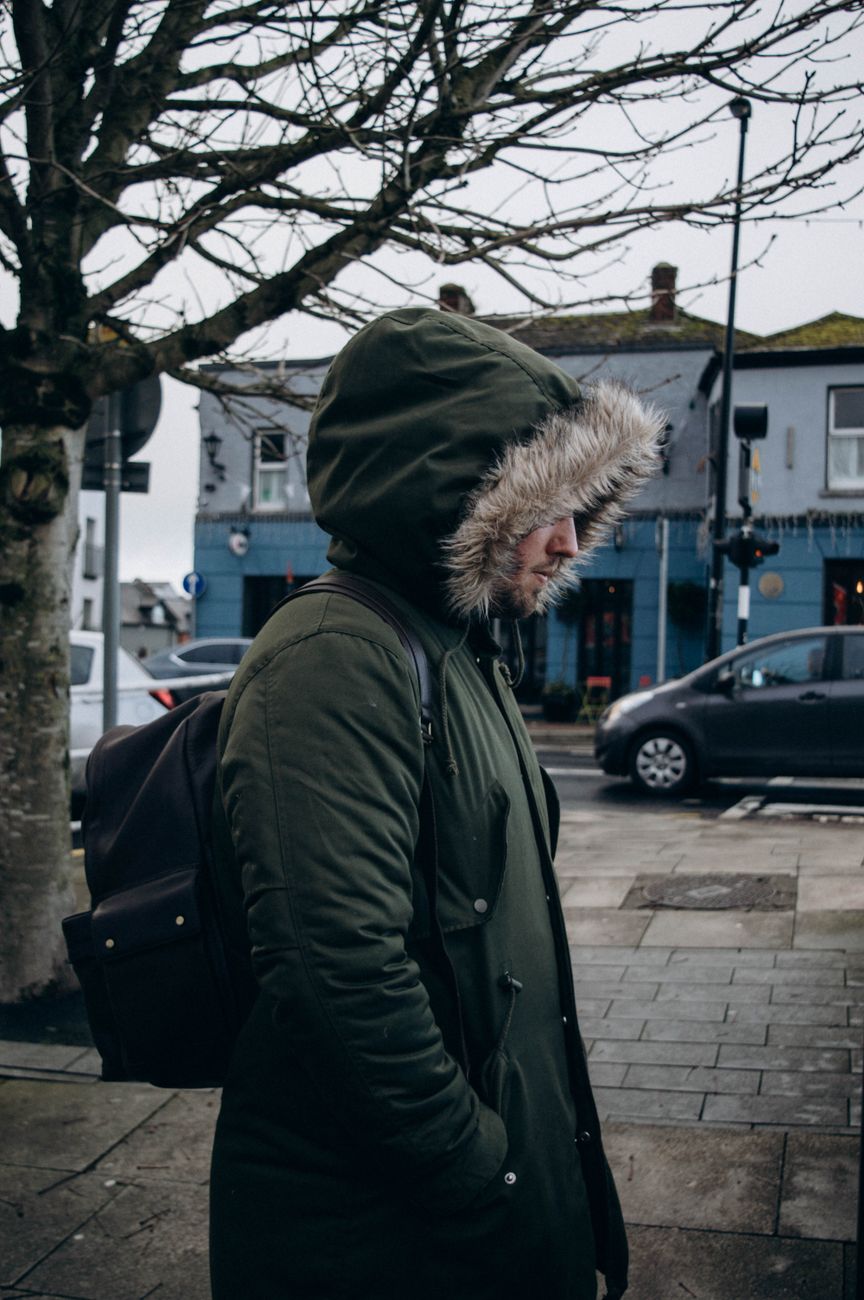 Muškarac u sivoj parki na tramvajskoj stanici